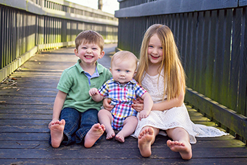 siblings sitting barefoot on a bridge at fort granger in franklin tn